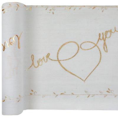 Un chemin de table mariage en coton blanc avec l'inscription love you, des cœurs et une frise de fleurs le tout coloris or métallisé vendu en rouleau de 3 mètres.