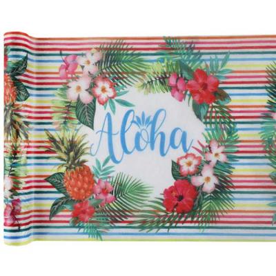 Chemin de table Aloha multicolore largeur 30 cm rouleau de 5 mètres, fond blanc imprimé de nombreuses rayures multicolores interrompu par un cercle entouré de fleurs exotiques portant au centre l'inscription ALOHA.