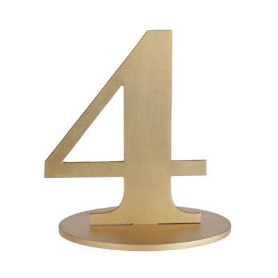 En bois coloris or, le chiffre 4 posé sur son  support à utiliser comme marque table ou en déco de table anniversaire.