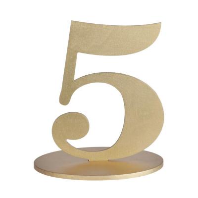 En bois coloris or, le chiffre 5 posé sur son  support à utiliser comme marque table ou en déco de table anniversaire.