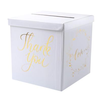 Une urne tirelire mariage blanche de 24 cm x 24 cm avec les inscriptions Thank you et Love coloris or métallisé