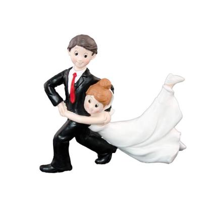 Figurine en résine représentant le marié en smoking noir et cravate rouge dansant avec la marié en robe blanche