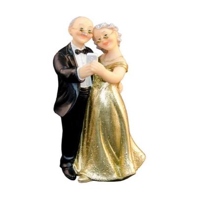 Figurine d'un couple de mariés fêtant leurs noces d'or, vêtus de noir et or, faisant un selfie