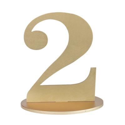 En bois coloris or, le chiffre 2 posé sur son  support à utiliser comme marque table ou en déco de table anniversaire.